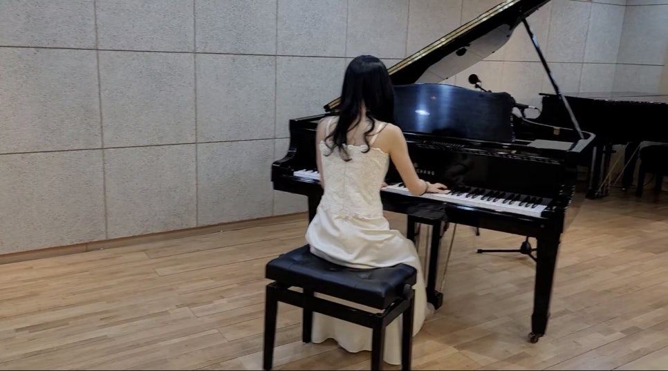 그랜드 피아노 앞에 앉아 연주하는 뒷모습